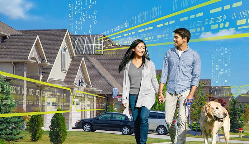 Man and a woman walking their dog in front of a house with Solar panels on its roof