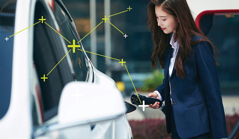 Woman dressed in a business clothes charging an electric car