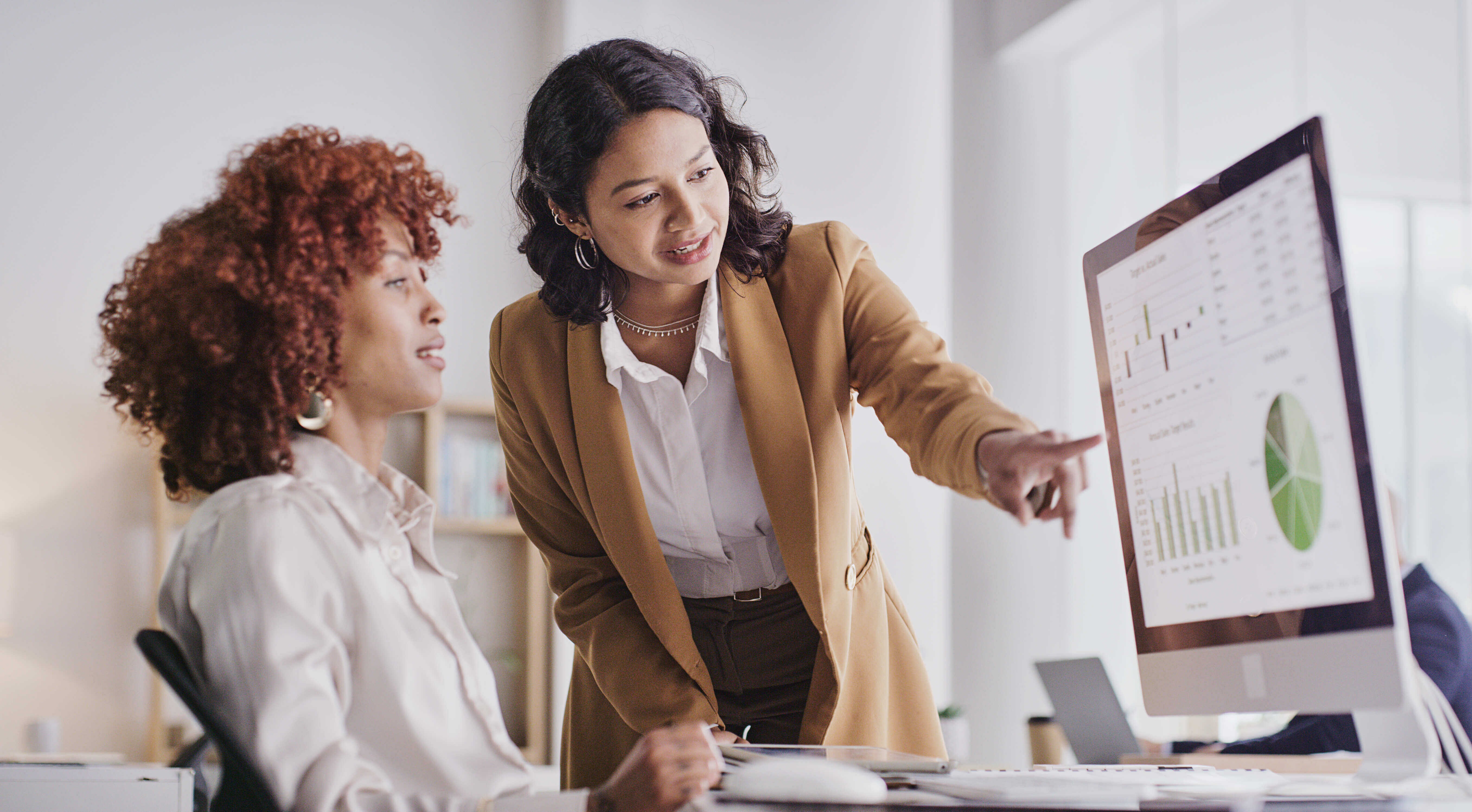 Two women looking at the computer and analytics